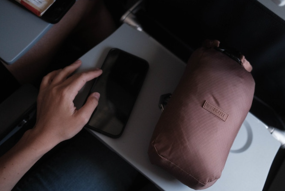 a hand holding a phone next to a bag
