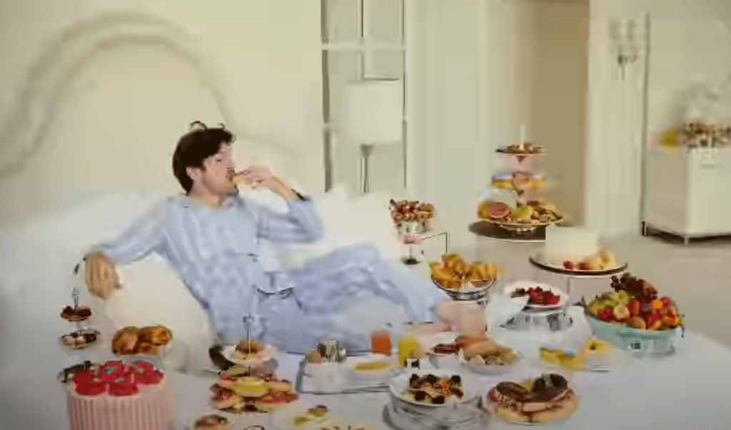 a man in pajamas eating food on a bed