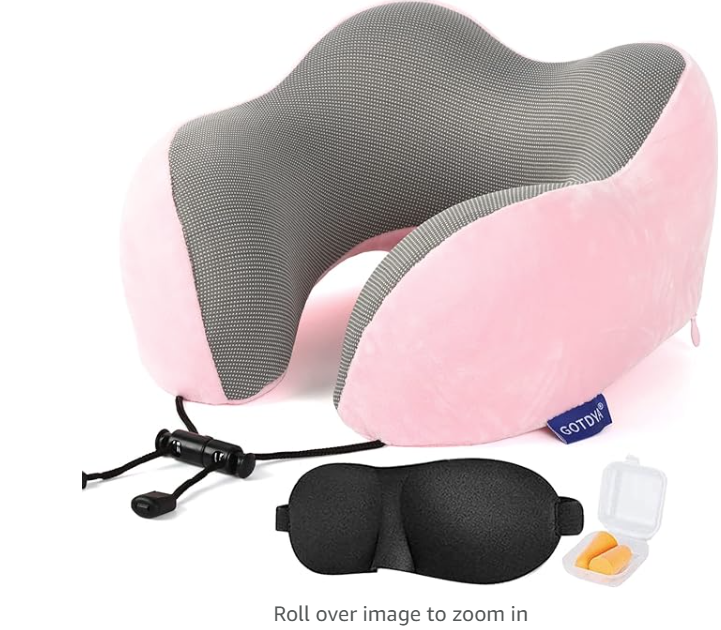 a pink and grey neck pillow with a black eye mask and ear buds