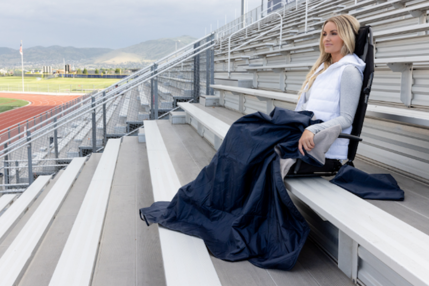 a woman sitting on bleachers with a blanket
