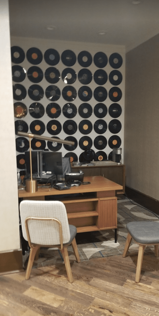 a desk with a computer and record wall