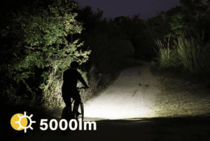 a person riding a bicycle on a dirt road at night