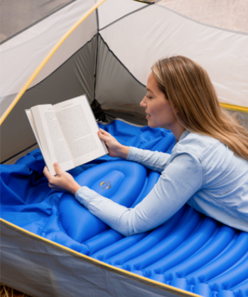 a woman reading a book in a tent