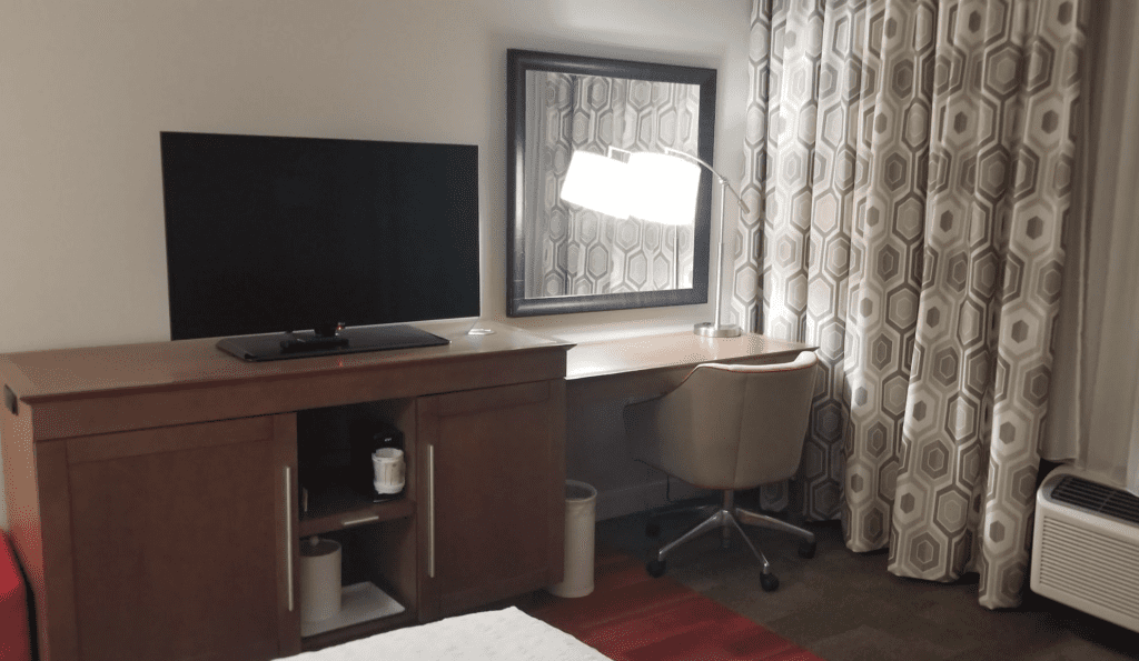 a desk with a lamp and a mirror in a room