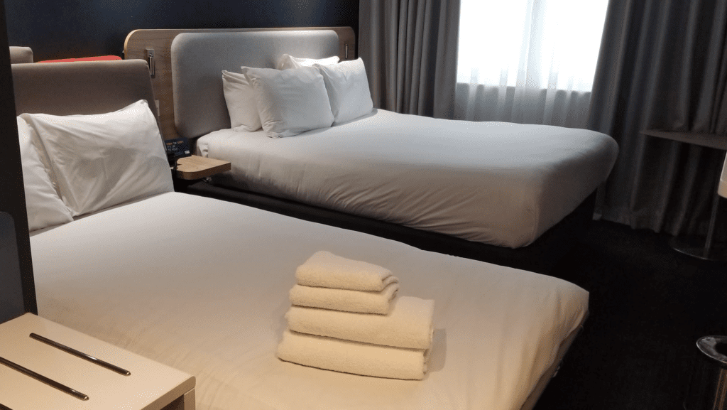 a room with two beds and a bed with a stack of towels
