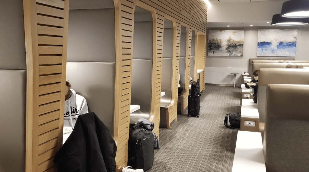 a person sitting in a row of booths with luggage