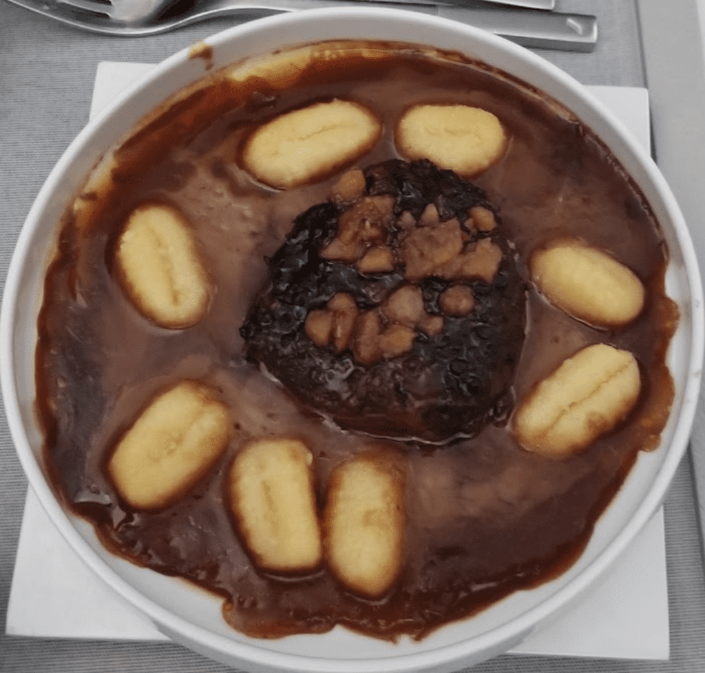 a bowl of food with brown sauce and small bananas