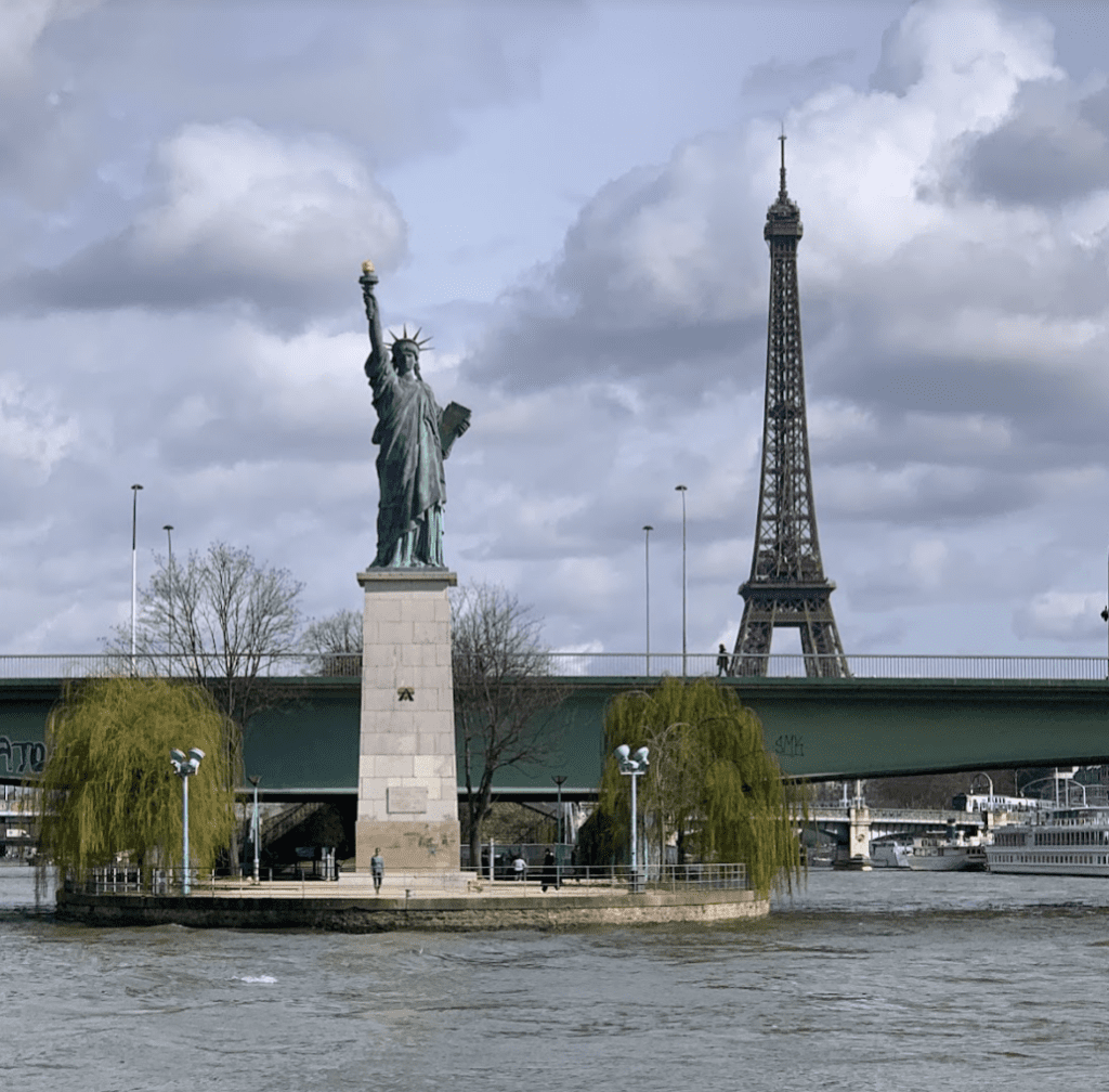a statue of a woman on a small island with a bridge and a tower
