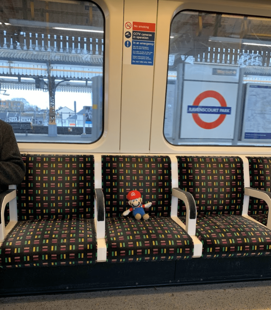 a man sitting on a train seat with a stuffed toy