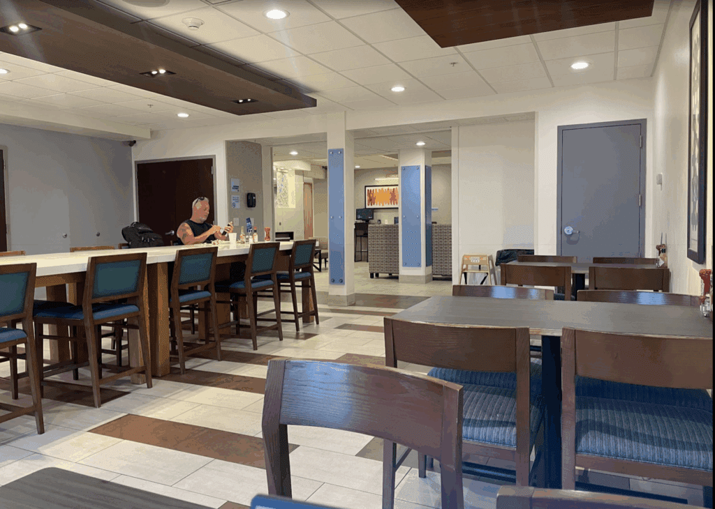 a man sitting at a table in a room with chairs and a door