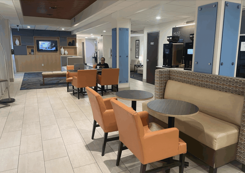 a man sitting at a table in a room with chairs and a television