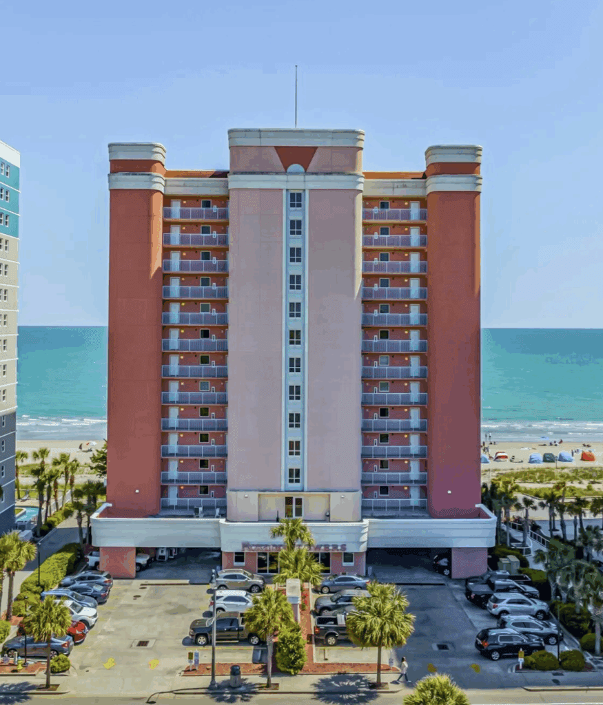 a large building with cars parked in front of the ocean