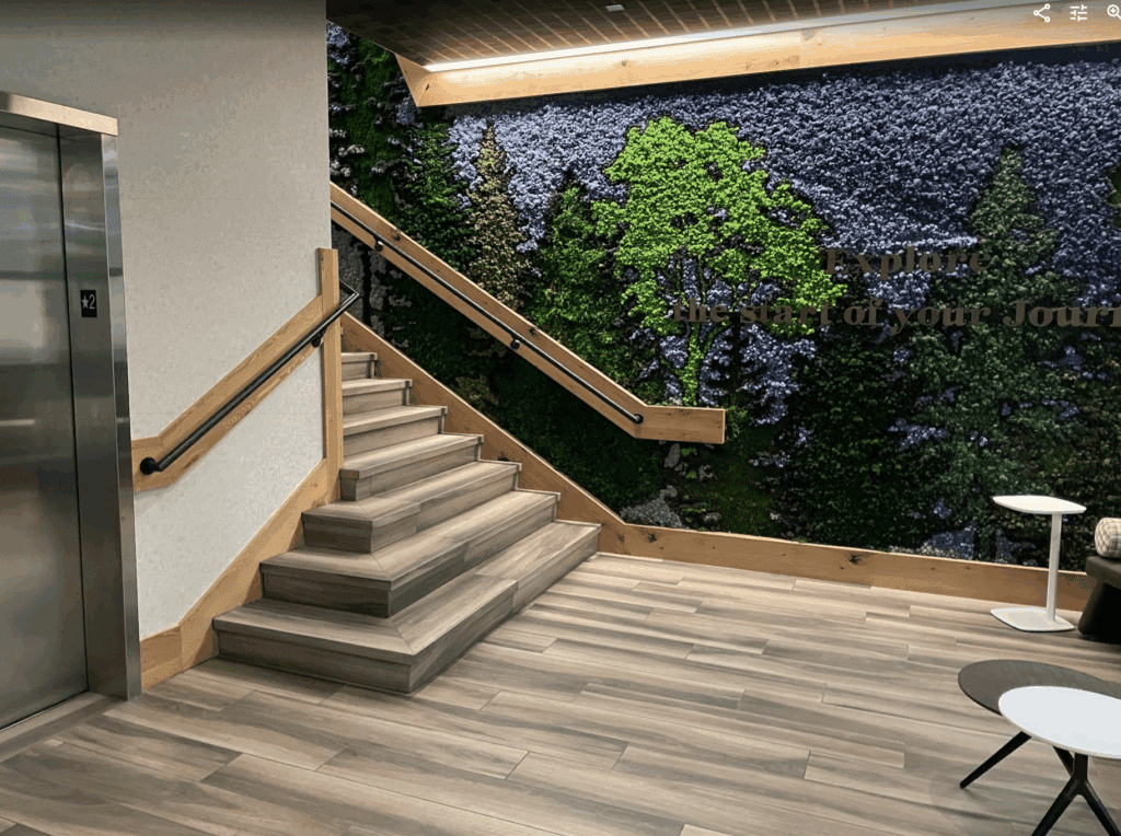 a staircase with a wall of plants and a picture on the wall