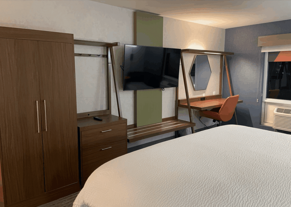 a room with a bed and desk and a mirror