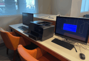 a desk with computers and a printer
