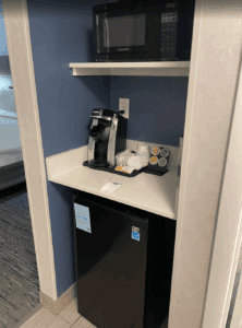 a small refrigerator and coffee maker on a shelf