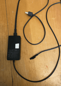 a black power cord on a wood surface