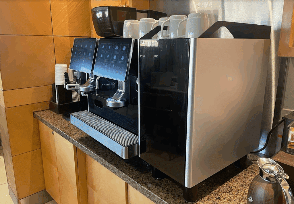 a coffee machine with a screen and cups on it