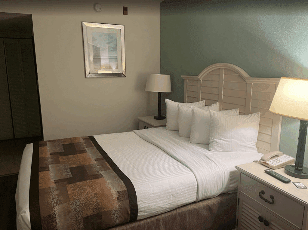 a bed with white pillows and a lamp in a room