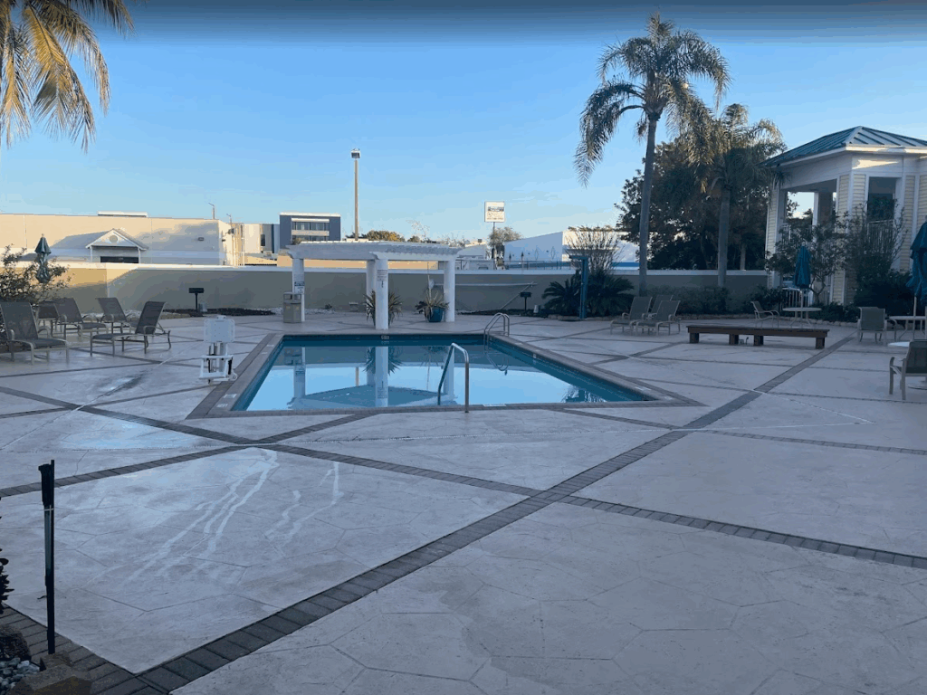 a pool with chairs and a building in the background