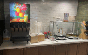 a counter with a drink dispenser and a pan