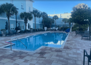 a pool with chairs and palm trees in front of a building