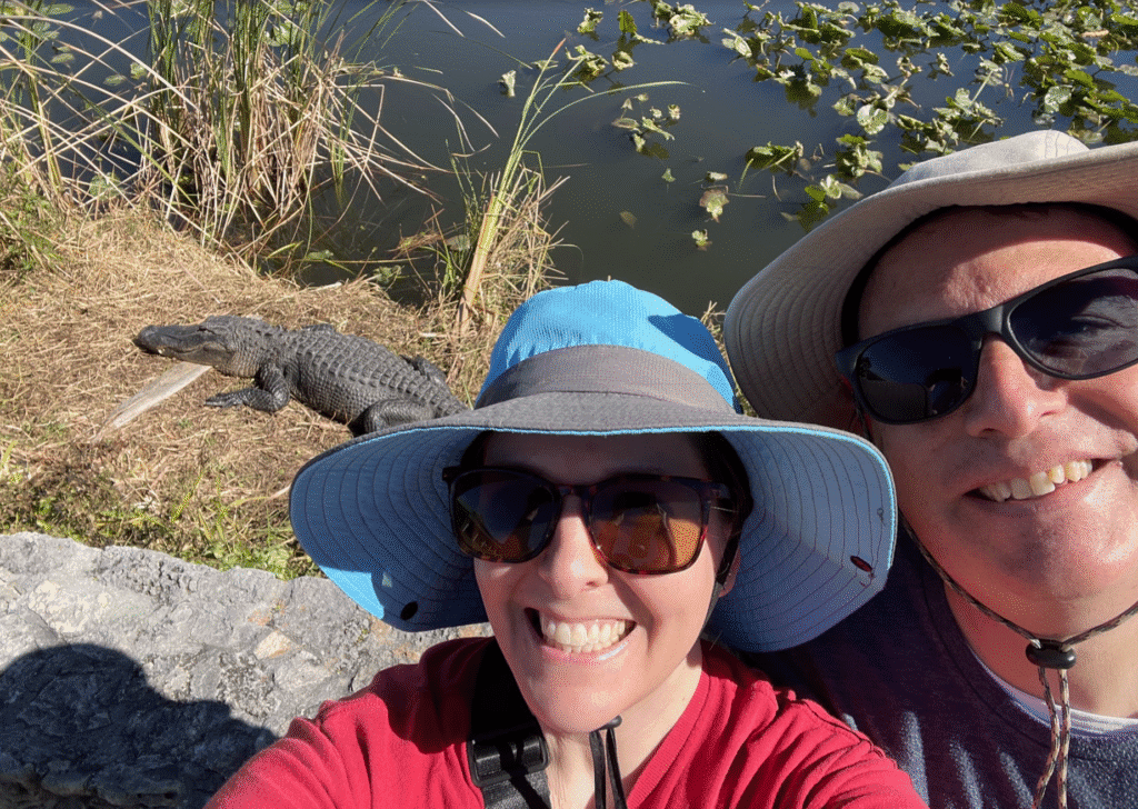a man and woman taking a selfie with a crocodile