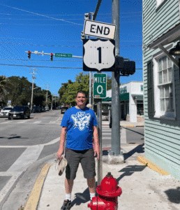 a man standing on the sidewalk next to a sign